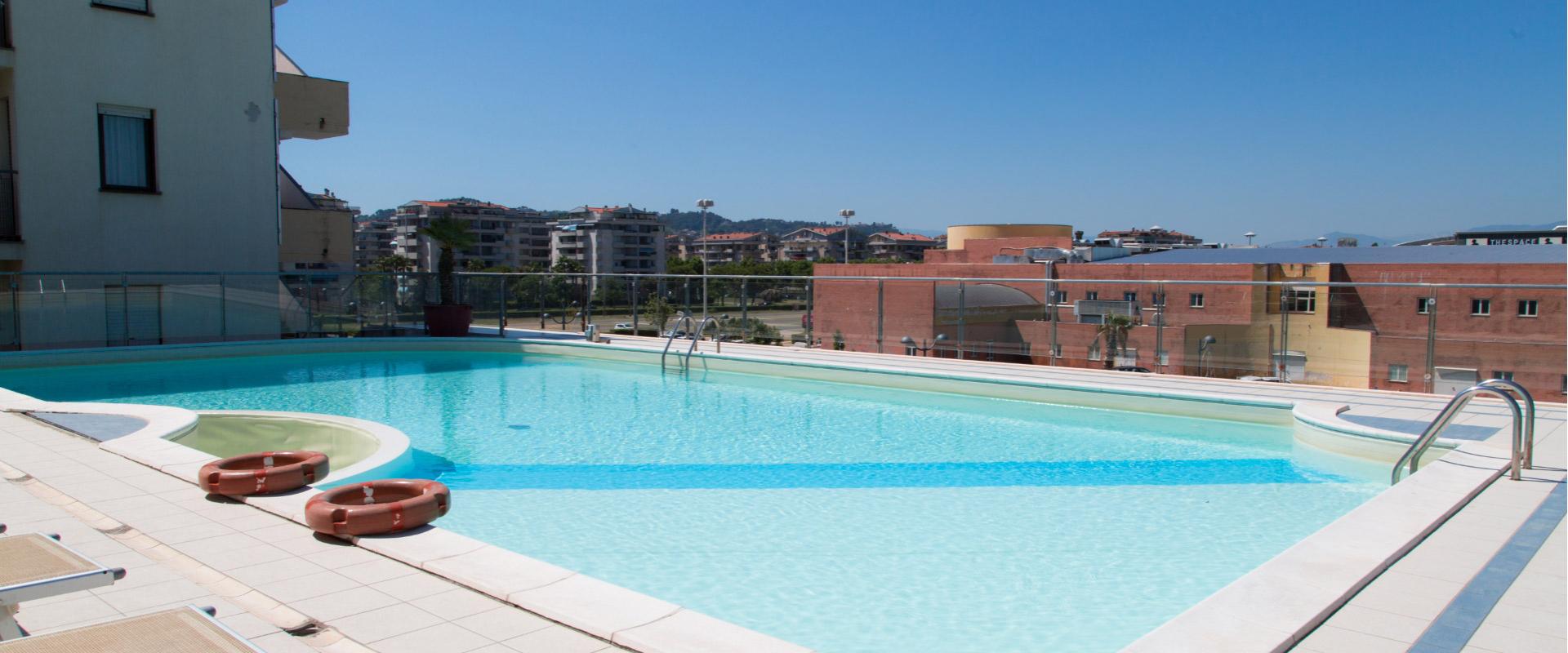 Piscina sul tetto con vista sulla città e lettini a bordo.
