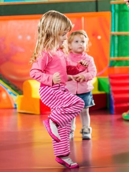 Bambine giocano in uno spazio colorato, indossando abiti rosa e a righe.