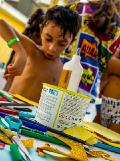 Bambini impegnati in un'attività creativa con carta, forbici e colla.