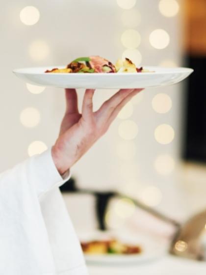Un cameriere serve un piatto elegante in un ambiente raffinato con luci soffuse.