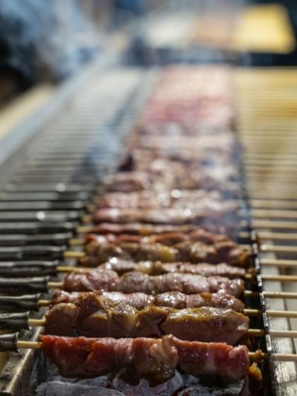 Spiedini di carne grigliati su barbecue, cotti su griglia con fumo.