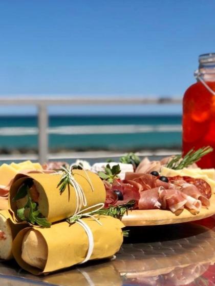 Antipasto di salumi e pane, con vista mare e bevanda rinfrescante.